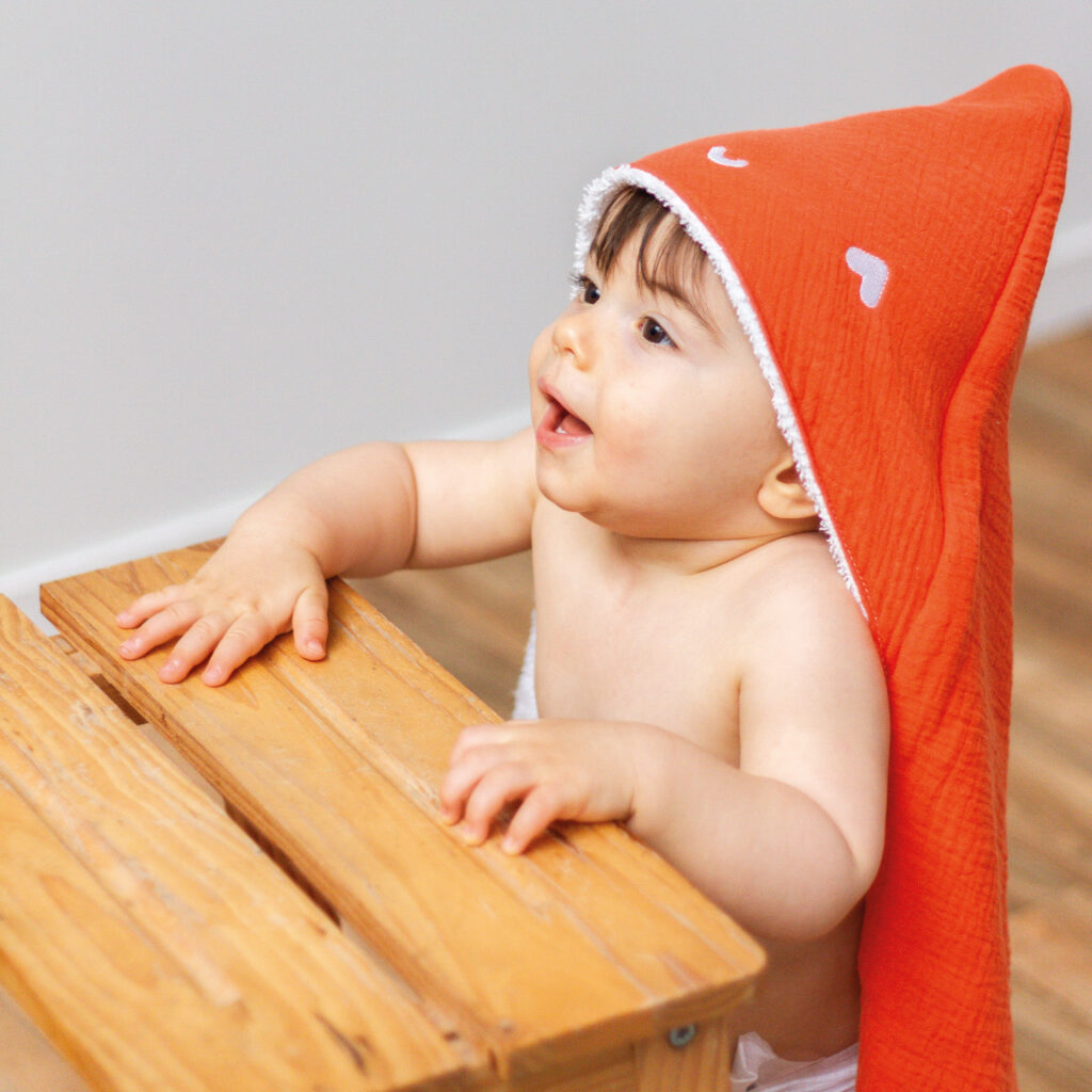 Enfant portant une cape de bain orange sur la tête