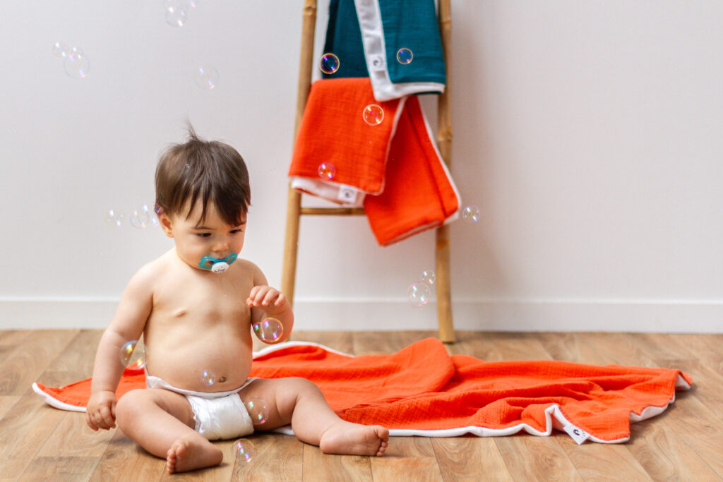 Enfant avec un plaid orange doux adapté pour les siestes.