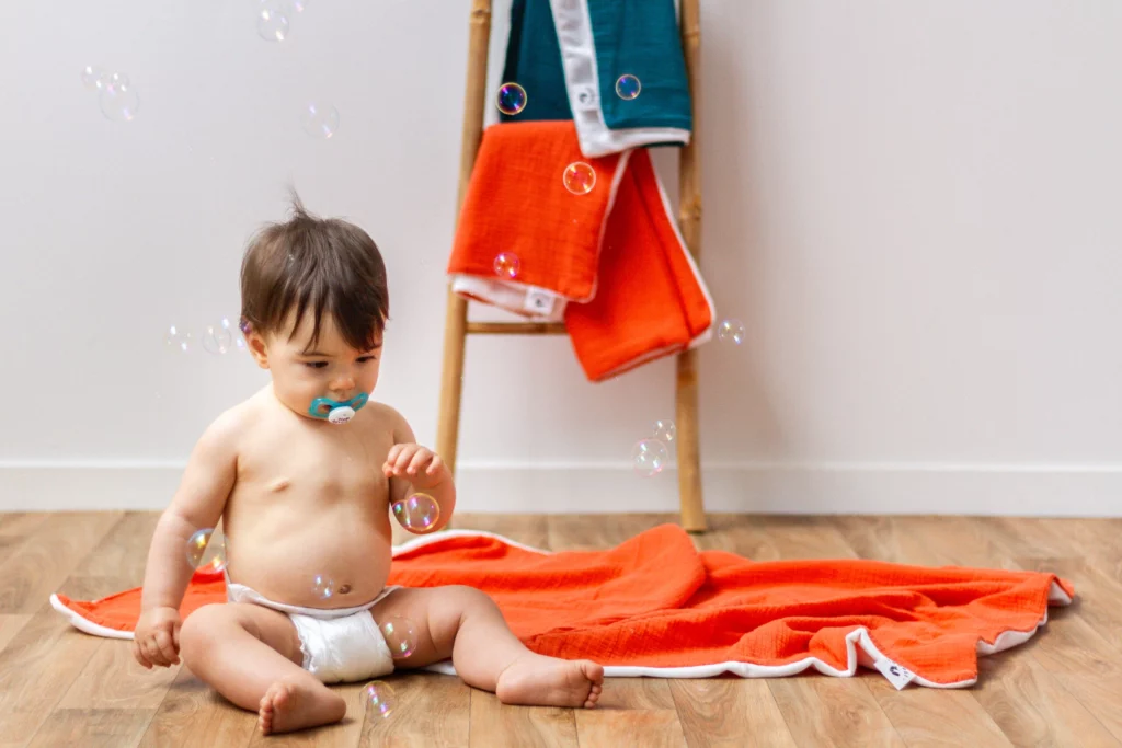 Enfant avec un plaid orange doux adapté pour les siestes.