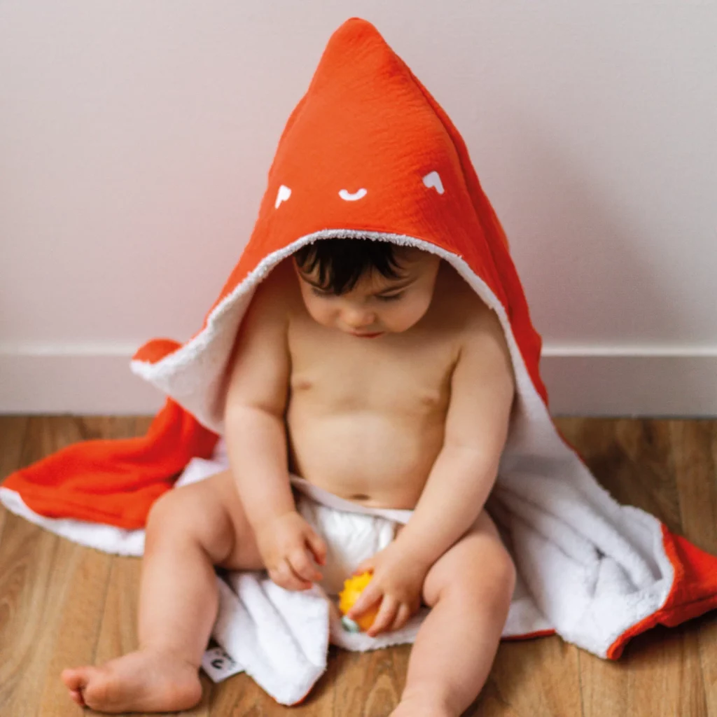 Enfant jouant en portant une cape de bain orange de la marque Toupli
